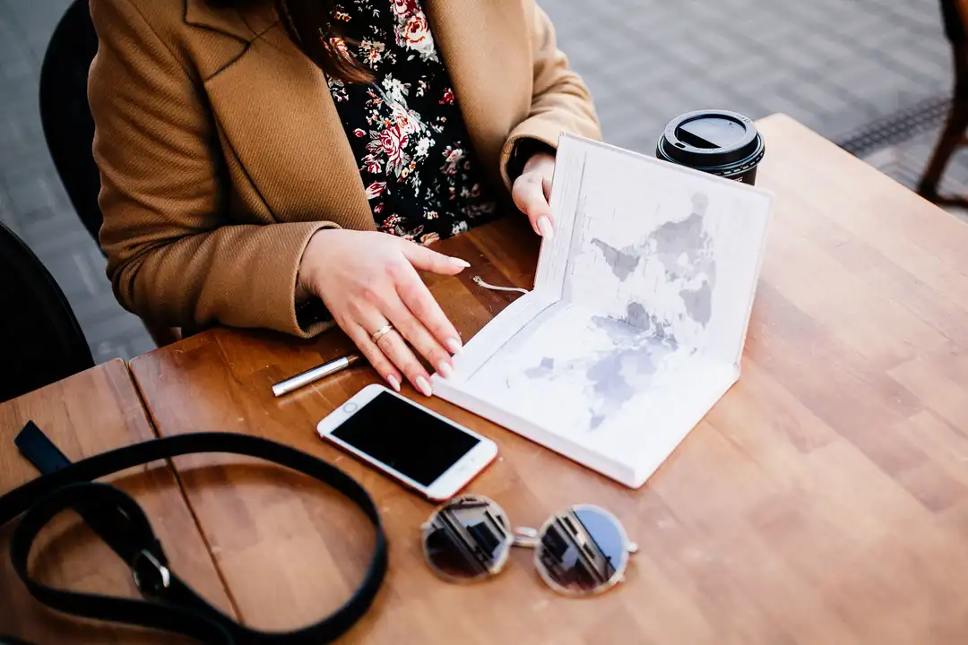 Bureau de travail : ordinateur avec du code, carnet d'itinéraires ouvert, appareil photo, carte